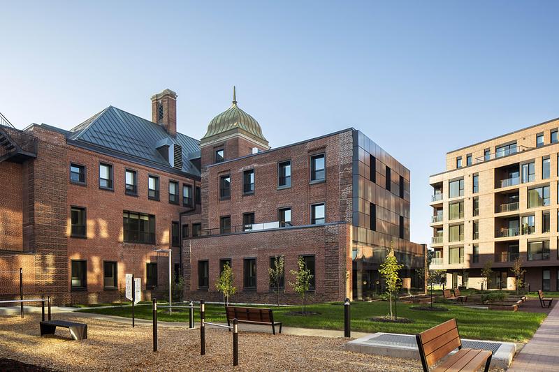 Brick heritage building beside planted pedestrian paths and a bench