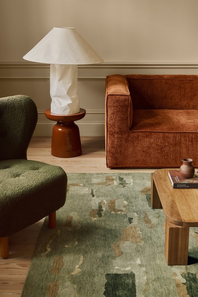Green patterned rug beneath an orange sofa and a wooden table