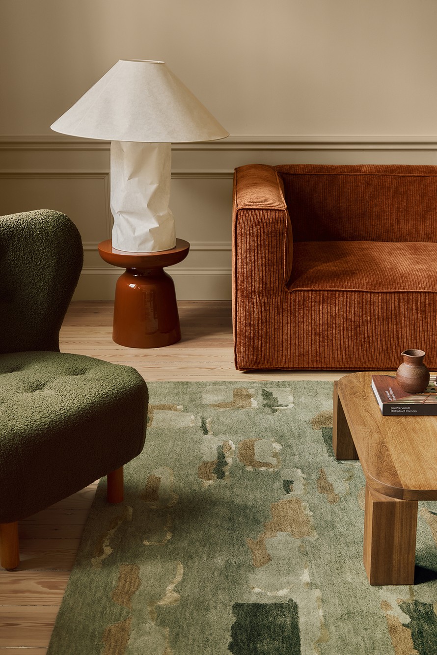 Green patterned rug beneath an orange sofa and a wooden table